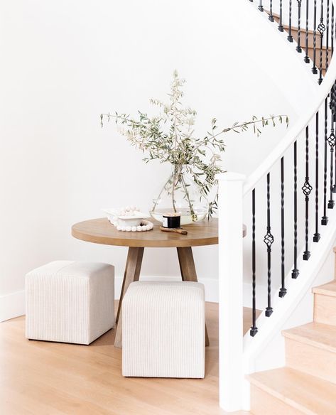 When you walk into our new home, you are greeted by this impressive circular staircase. I wanted to create an inviting focal point as you come through the door in this unique curved space. This simple, 48" round table fit perfectly and I paired it with these darling ottomans by @studiomcgee. A large glass vase filled with fresh branches cut from the yard and tabletop accessories finish it off beautifully! 🖤⁠ ⁠ Email/message me if you need links to any of these items! ✔️⁠ ⁠ #tomkatstudio #... Entryway Decor Round Table, Foyer Ideas Entryway Round Table, Round Table Entryway Decor, Circular Entry Table, Curved Entryway Ideas, Round Table Entryway, Round Entry Table Decor, Round Foyer Table Decor Entryway, Foyer Round Table