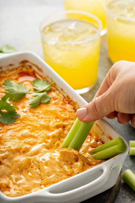 Hand dipping a celery stick into buffalo chicken dip in a white casserole dish Small Buffalo Chicken Dip, Single Serve Buffalo Chicken Dip, Hellmans Buffalo Chicken Dip, Individual Buffalo Chicken Dip, Buffalo Chicken Dip Allrecipes, Appetizer Dips Hot, Spicy Buffalo Chicken Dip, Buffalo Dip, Buffalo Chicken Dip Crock Pot