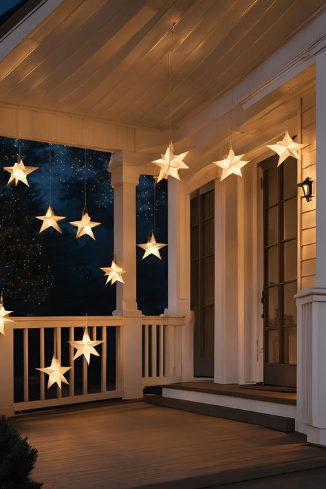 Front porch decorated with Christmas hanging star lanterns, garland, and twinkling lights along the railing for a warm holiday welcome. Christmas Lights On Houses Exterior, Hanging Lights Front Porch, Christmas Lights On Front Porch Railing, Front Porch Hanging Christmas Decor, Diy Outdoor Star Christmas Lights, Christmas House Lights Exterior, Holiday Exterior Lights, Simple Outdoor Lights Christmas, Outdoor Star Decoration