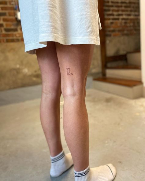 Teeny tiny cowboy boot tattoo Cowboy Boot Tattoo Placement, Rain Boot Tattoo, Tiny Cowboy Boot Tattoo, Dainty Leg Tattoos, Boots Tattoo, Boot Tattoo, Cowboy Boot Tattoo, Swift Tattoo, Taylor Swift Tattoo