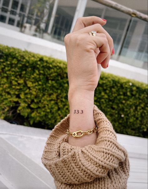 A woman’s for showing an angel number tattoo on the outside of her wrist, it says 333. 333 Minimalist Tattoo, Fine Line 333 Tattoo, 333 Wrist Tattoo, Vertical Number Tattoo, Minimalist Number Tattoo, Angel Number 333 Tattoo, 333 Angel Number Tattoo Ideas, 333 Angel Number Tattoo, 333 Tattoo Fonts