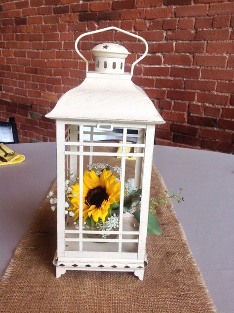 White lantern with a sunflower arrangement inside. Lanterns With Sunflowers, Sunflower Sweet 16, Sunflower Party Ideas, Sunflower Lantern, Sunflower Wedding Centerpieces, Party Decorating Ideas, Sunflower Arrangement, Sunflower Wedding Decorations, Lantern Centerpiece Wedding