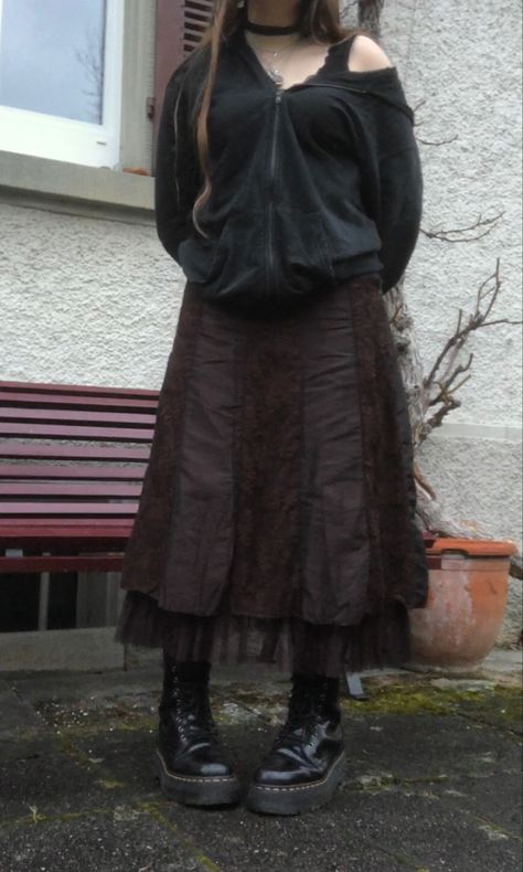 A mid-size person/girl wearing mate rose lipstik, a black tight lace strap top with a black zip-up hoodie and a thrifted dark brown maxi skirt, black dr. Martins and multiple crystal rings and bracelets. 	The person is also wearing multiple silver necklaces, one in form of a crystal heart and another in form of a moon, a green fairy necklace and a black lace choker. Brown Lace Skirt, Brown Maxi Skirt Outfit, Earth Tone Grunge, Fit Aesthetic Outfit, Brown Skirt Outfit, Plus Size Grunge, Jewelry Lace, Grunge Outfits Winter, Brown Maxi Skirt