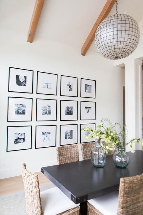 Beautiful dining room features a Restoration Hardware Capiz Shell Pendant illuminating a rectangular black dining table lined with wicker dining chairs placed in front of a wall lined with a black and white photo gallery. Minimalist Dining Room Decor, Dining Room Gallery Wall, Dining Room Trends, Family Pictures On Wall, Big Wall Decor, Minimalist Dining Room, Photo Wall Gallery, Popular Decor, Beautiful Dining Rooms