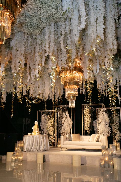 This glam wedding reception focuses on hanging florals & statement chandeliers | Wedding, wedding design, wedding designer, luxury wedding designer, event designer, event styling, luxury wedding, wedding 2023, luxury wedding reception, luxury wedding decor, wedding reception decor, wedding reception ideas, glamorous wedding decor, elegant wedding decor, Indian wedding reception, wedding stage decor, event floral design, wedidng floral inspiration,black and gold wedding #weddingreception #wedding Black And White Wedding Stage, White Indian Wedding Decor, Reception Decorations Indian, Classy Indian Wedding, Ethereal Wedding Reception, White Reception Decor, Black White Gold Wedding Theme, Glam Wedding Reception, Gold Reception Decor