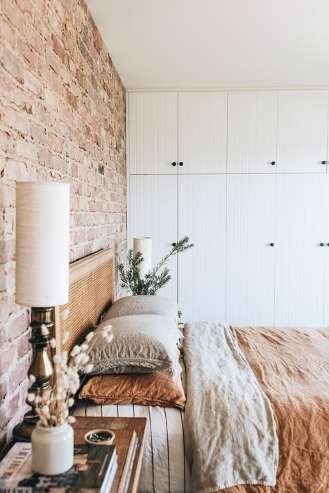 The bedroom of this modern country home in Tasmania features an exposed brick wall and linen sheets. Australian Country Bedroom, Bedroom With Exposed Brick, Brick Wall In Bedroom, Country Modern Bedroom, Brick Wall Interior Bedroom, Red Brick Bedroom, Painted Brick Wall Interior, Exposed Brick Walls Bedroom, Bedroom With Brick Wall