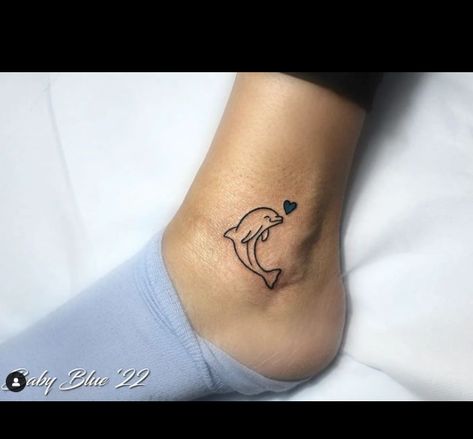 The dolphin tattoo represents love and peace, as shown by the blue heart in this tattoo. The dolphin is friendlier, and its bright smile and excellent performance are constant reminders of children laughing. It is a charming tattoo representing love,... Dolphin Wrist Tattoo, Small Dolphin Tattoo Designs, Dolphin Heart Tattoo, Dolphin Tattoo For Women, Small Dolphin Tattoo, Tattoo Dolphin, Charming Tattoo, Memorial Tattoos Mom, Dolphin Tattoos