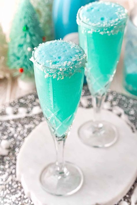 A gorgeous hue of blue, a Jack Frost mimosa, with its frosty rim of coconut,  is a spectacular addition to your brunch or holiday party. Appetizers In Champagne Glasses, Tiffany Blue Cocktail Drink Recipes, Tiffany Blue Drinks Cocktails, Tiffany Blue Mimosa, Cotton Candy Mimosa Bar, Christmas Drinks With Blue Curacao, Drinks Made With Champagne, Tiffany Mimosa Recipe, Blue Mimosa Bar