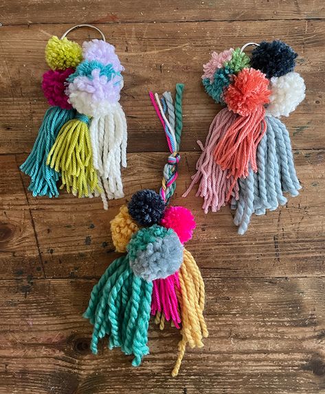 3 finished pom-pom tassel hangers on a table in different color schemes Tassel Pom Pom, Fabric Pom Poms, Tassel Diy, Pom Pom Mobile, Best Scissors, Diy Pom Poms, Book Rings, Big Yarn, How To Make A Pom Pom