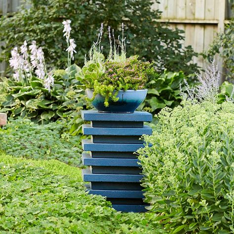 Dress up your outdoor space with DIY planters. This pedestal of stacked concrete pavers raises up a bowl into a focal point planter. The bowl is filled with succulents and water-wise plants as shallow containers call for plants that won’t fade if you miss a day of watering. Driveway Columns Ideas, Garden Pedestal Ideas, Garden Boxes Ideas, Angelina Sedum, Mexican Heather, Garden Pedestal, Planter Pedestal, Concrete Pedestal, Landscaping Blocks