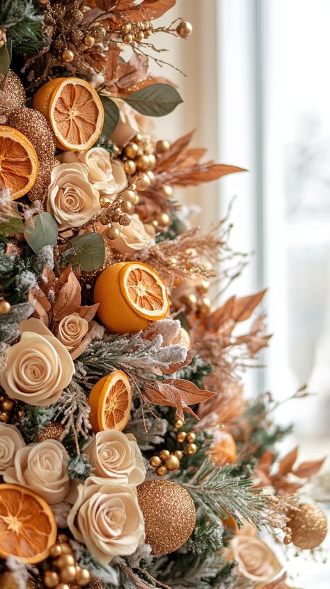 Close-up of a decorated Christmas tree with dried orange slices, flowers, and gold accents against a beige wall and white White And Orange Christmas Tree, Orange Christmas Decorations Color, Christmas Tree With Dried Oranges, Oranges Christmas Decoration, Sugared Fruit Christmas Decor, Dried Oranges Christmas Tree, Christmas Tree Oranges, Burnt Orange Christmas Decor, Orange Christmas Aesthetic