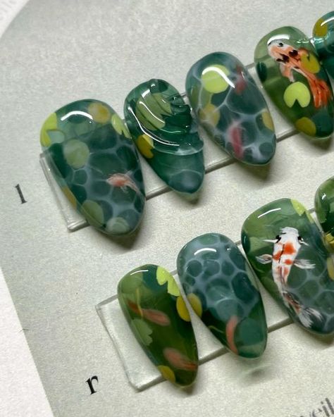 Veiled Nails on Instagram: "𝒌𝒐𝒊 🎏  Been wanting to do a koi fish set in a while! Complete with waterlilies 😌  ✦ 𝑺𝒊𝒛𝒆 𝒂𝒏𝒅 𝑺𝒉𝒂𝒑𝒆 - Medium Almond Natural @apresnailofficial ✦ 𝑭𝒍𝒂𝒔𝒉 𝑺𝒆𝒕  ✦ Using @sweetienailsupply Jin.B Crazy Top and @agehagel @trinagel_official  colours 。 。 。 。 。 。 #koinails #fishnails #koifishnails #koipond  #水墨画 #handpainted #3dnails #3dnailart #3dネイル #うるうるネイル #bluenails #nuancenails #pressons #veilednails #pressonnails #waternails #clearnails #greennails" Water Lily Nail Art, Pond Nail Art, Koi Nail Art, Nails With Fish, Koi Pond Nails, Goldfish Nails, Koi Fish Nail Art, Pond Nails, Koi Nails