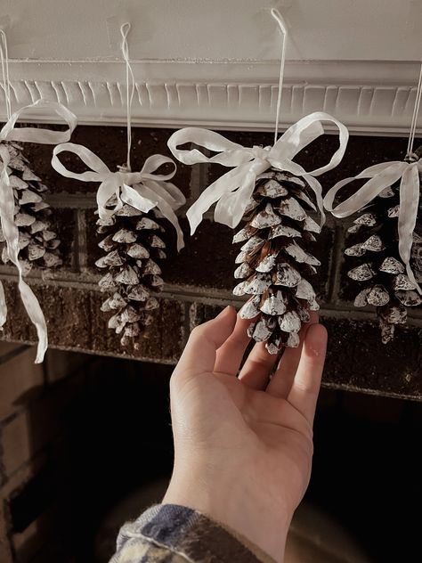 These delicately adorned pine cones add the perfect element of nature's beauty to your winter home. Each cone was carefully selected from the forest floor on a blustery autumn day, painted with festive/seasonal colors, and tied with a bow to complete their look of elegance. Whether they are hanging from the edge of your mantel, strung across window panes, or dangling from the boughs of your Christmas tree, these pinecones are a delightful addition to your Holiday season decor! Xmas Pine Cone Decorations, Pinecone Trees Diy, Pine Comb Christmas Tree, Decoration Noel Nature, Pine Cone Ornaments, Pinecone Art, Pinecone Crafts, Diy Snow Covered Pinecones, Snow Covered Pinecones