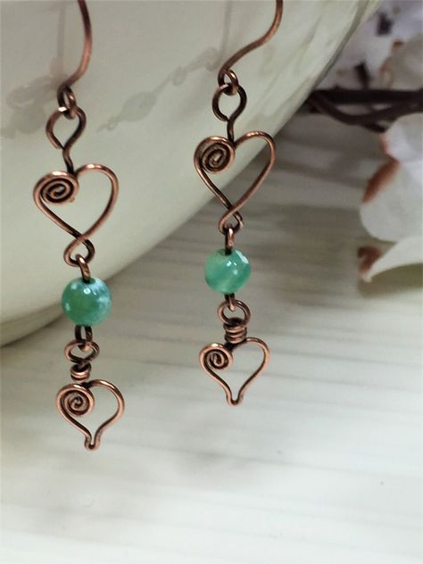 Beautifully wire wrapped heart shaped copper earrings with a mint green fire agate cracked onyx stone. Copper is patinated/oxidized and polished to give a rustic and aged look. This is great to wear on valentines day or a perfect gift to your loved ones! If you prefer another color stone, please send a message to check if I have that in stock. If I have it in stock I will be glad to change the bead color! NOTE: All jewelry in my shop are handcrafted by me. The beauty of handcrafted jewelry is no two pieces are the same, unlike mass productions. The pieces that you may receive may have slight variation from the pictures. If you like any of the pieces from my shop but are interested in a slight variation or different color, please reach out to me.  I will try my best to recreate it per your Artisan Jewelry Wire, Valentines Wire Jewelry, Wire Wrapped Jewelry Heart, Elegant Handmade Jewelry, Copper Beaded Earrings, Heart Wire Earrings, Diy Wire Wrapped Earrings, Valentine Jewelry Diy, Handmade Jewellery Design