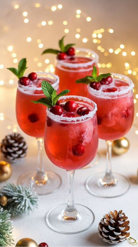 Festive cranberry cocktails in stemware, garnished with mint leaves and cranberries, surrounded by holiday decorations. Wine Mixers Recipe, Champagne Flute Desserts, Cranberry And Champagne Drink, Glitter Christmas Cocktails, Sparkling Cocktail Recipes, Cranberry Alcoholic Drinks Holidays, Winter Cranberry Cocktails, Holiday Prosecco Cocktails, Drink Recipes With Prosecco