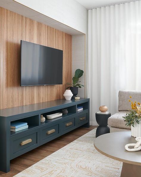 A low blue TV cabinet sits on a reeded trim wall under a mounted TV with a tan rug. Decor Under Tv Wall Mounted Tv Living Room Ideas, Wall Mounted Tv Living Room, Decor Under Tv Wall Mounted Tv, Blue Tv Cabinet, Under Tv Cabinet, Mounted Tv Living Room, Decor Under Tv, Tv Living Room Ideas, Trim Wall