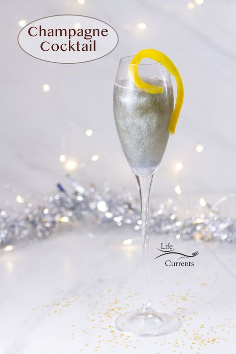 A sparkling Champagne Cocktail in a Champagne glass with a lemon twist in front of silver sparles and twinkle lights. Silver Alcoholic Drinks, Silver Drinks Cocktails, Silver Cocktail, Nye Champagne Drinks, Glitter Drinks Alcohol, Winter Champagne Cocktail, Glitter Champagne Drink, Champagne Drinks New Years Eve, New Year’s Eve Champagne Drinks