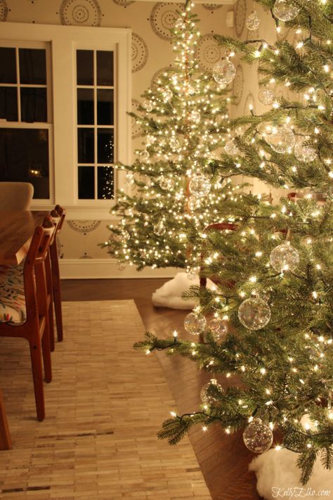 Glowing Christmas Tour at Night - love the pair of glowing sparse trees with clear glass ornaments kellyelko.com #christmasdecor #christmastrees #sparsechristmastrees #christmaslights #christmasdiningroom #christmasornaments #clearornaments #diychristmas #christmascrafts #kellyelko #farmhousechristmas #fixerupperstyle Twinkle Light Tree, Twinkling Christmas Tree Lights, Christmas Tree Lighting Event, Dyker Heights Christmas Lights Brooklyn, Bubble Christmas, Clear Christmas Ornaments, Dyker Heights Christmas Lights New York, Clear Glass Ornaments, Christmas Apartment