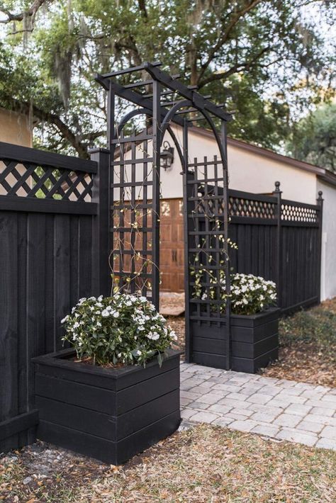 Black Vinyl Fence Front Yard, Black Wood Fence Backyards, Wood Fence With Metal Gate, Front Yard Arch Entrance, Wood Fence Decorations, Diy Trellis Archway, Fenced In Patio, Black Wood Fence, Natural Paths