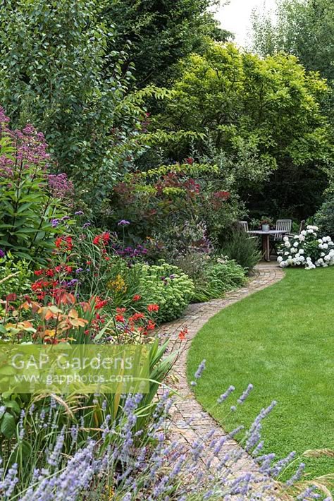 View of brick path beside an herbaceous border and a lawn leading to seating area in the shade of Magnolia and other trees Curved Borders Garden, Garden Path Through Lawn, Brick Path Garden, Herbaceous Border Design, Path Through Lawn, Garden Paths Through Lawn, Small Garden Path, Brick Garden Path, Path Border