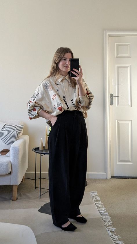 A woman stands in front of a mirror. She wears an oversized embroidered shirt with wide leg black trousers and black Mary Jane shoes. Wide Leg Trousers Shoes, Wide Legged Black Pants Outfit, Brown Palazzo Pants Outfit, Oversized Shirt Outfit Winter, Wide Black Trousers Outfit, Wide Leg Office Outfit, Oversized Black T Shirt Outfit, Wide Trousers Outfit Winter, Oversized Trousers Outfits