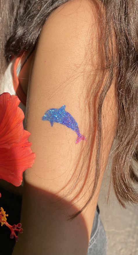 girls arm with a dolphin glitter tattoo on it. the tattoo is blue pink and purple Glitter Tattoo Aesthetic, Coconut Girl Tattoo, Glitter Tattoo Ideas, Beach Girlies, Bestie Crafts, Glitter Henna, Sparkle Tattoo, Cute Henna Tattoos, Dolphins Tattoo