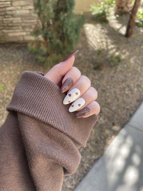 Chocolate brown nails with two white accent nails with small brown hearts 🤎 #nails #nailart #brownnails #brownaesthetic #heartnailart #heartdesign #heartnails #trendynailart #nailinspo #nailideas #almondnails #gelnails #gelpolish #gelextenstion Brown Nails Design Almond Shape, Brown Black And White Nails, Brown Nails Thanksgiving, Brown Spooky Nails, Brown Hearts Nails, Cute Simple Brown Nails, Burberry Nails Brown, Teddy Bear Brown Nails, Cream Brown Nails