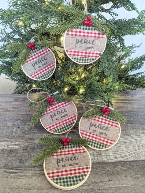 Peace on earth  These beautiful embroidery hoop ornaments add instant charm to your Christmas Tree. Each ornament is handmade with Bamboo wood hoops, soft green and red plaid material, a burlap ribbon that reads "peace on earth " At the top realistic green pine with faux red berries adds a beautiful touch .    Each ornament has a jute twine hanger which measures approximately 3" long .  Each ornament measures 5 inches with the greenery, but NOT including the burlap ribbon hanger .  This listing is for one ornament. Pair these ornaments with our other ornaments listings. Make sure to browse my other holiday decor.  Please note I do my best to make each item as consistent as possible. Each handmade item may have slight differences than what is shown in the photo. No two handmade items are ex Embroidery Hoop Christmas Ornaments, Embroidery Hoop Ornaments, Atc Coins, Hoop Ornaments, Acrylic Projects, Embroidery Christmas Ornaments, Embroidery Hoop Decor, Sewn Christmas Ornaments, Christmas Gift Tags Diy