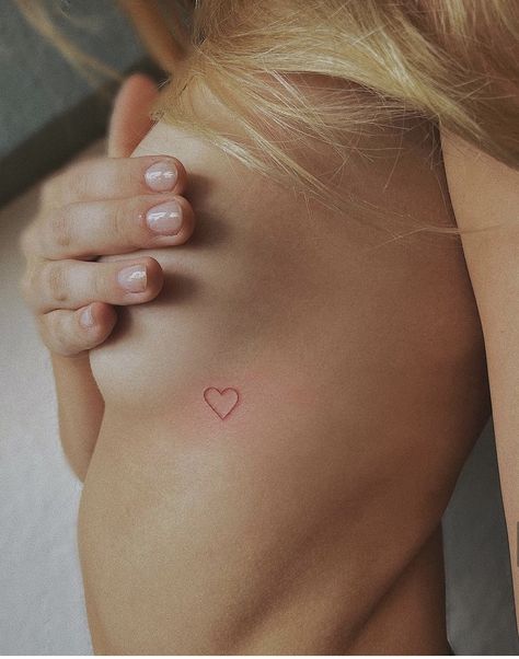 Red Tattoo Ribcage, Micro Red Heart Tattoo, Small Red Heart Tattoo On Chest, Tattoo Over Heart Placement, Small Red Heart Tattoo On Buttcheek, Heart Ribcage Tattoo, Heart Tattoo Ribcage, Small Heart Tattoo Placement, Tattpp Ideas Woman