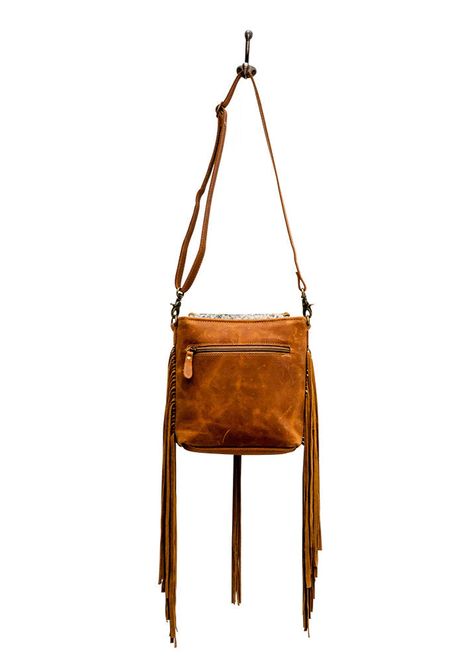 Get ready to make a statement with the Myra Tooled Leather Hairon Crossbody Bag! Featuring a unique blend of leather and hairon material, this bag has a playful fringe detail that adds a touch of bohemian style. Perfect for everyday wear, this crossbody bag will keep your essentials organized in a fashionable and fun way. Material: Hairon & Tooled Leather Dimensions: Width: 10", Height: 9", Shoulder: 22", Depth: 2.25" Tooled Leather, Leather Tooling, Bohemian Style, Crossbody Bag, Everyday Wear, Leather