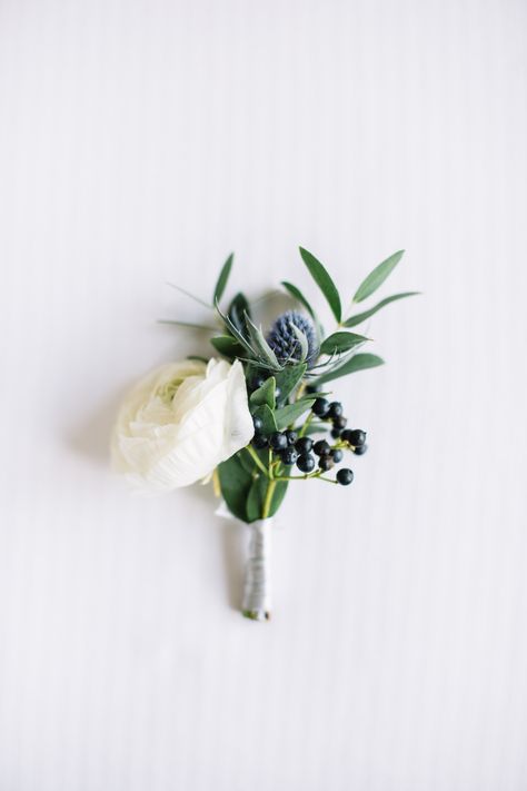 White ranunculus, eucalyptus and navy blue berries boutonniere perfect match for a modern and chic groom. Simple Mens Boutonniere, Eucalyptus Boutineer Groomsmen, Navy Suit Boutonniere, Mens Boutineers Wedding Navy Suit, Navy Blue Boutonniere Wedding, Minimal Boutonniere, Dark Blue Boutonniere, Navy Blue And White Boutonniere, Navy Blue And Greenery Bouquet