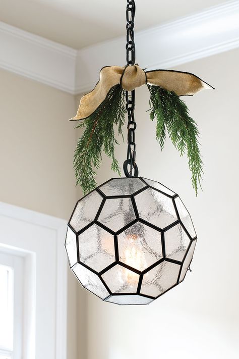 Pendant light with sprigs of greenery and ribbon Greenery On Pendant Lights, Ribbon On Pendant Lights, Decorate Light Fixture For Christmas, Decorating Light Fixtures For Christmas, Christmas Pendant Light Decor, Christmas Chandelier Ideas, Farmhouse Addition, Christmas Chandelier, Glass Light Fixtures