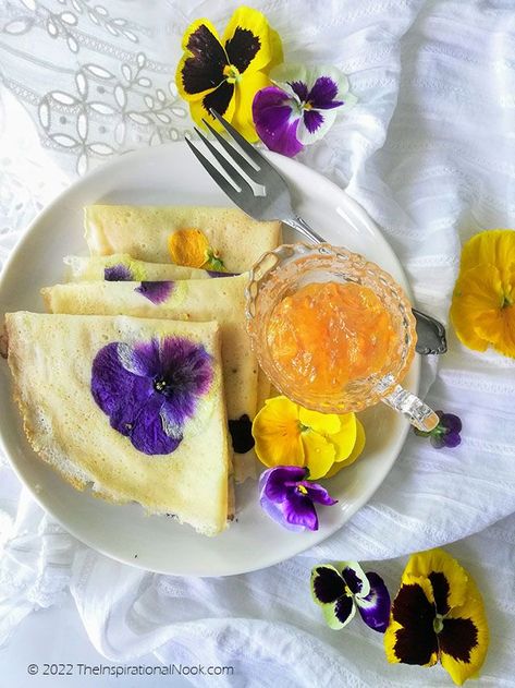 Purple and yellow pansies cooked with crepes or pancakes, served in a white plate with orange marmalade in a glass bowl, edible pansy petal pancakes Edible Flower Tarts, Beautiful Breakfast Ideas, Pansy Recipes, Dessert With Puff Pastry, Flower Pancakes, Fancy Pancakes, Cottage Core Recipes, Apple Rose Pastry, Rose Dessert