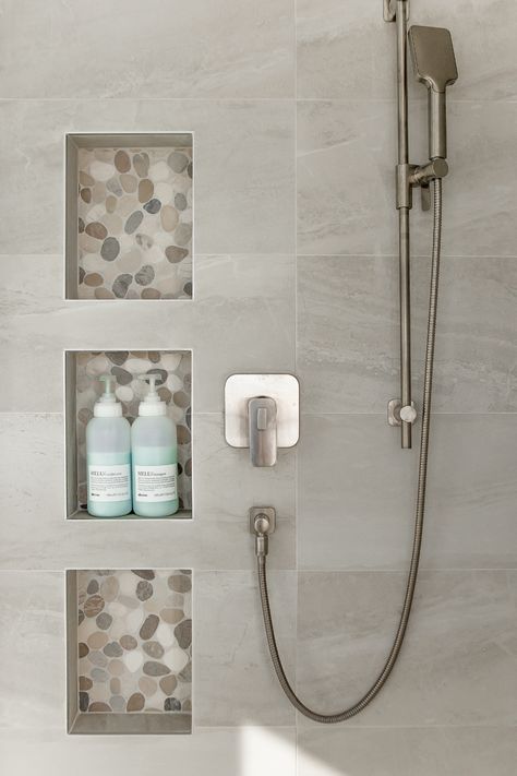 Your shower niche is the perfect opportunity to create some visual interest. Here we used a smooth river stone tile to draw the eye but also to create some material repetition as the tile was also used for the shower floor as well. Design by Kierstin Smyth Design. Photo Credit: Darren Lebeuf #edmontonbathroomrenovation #edmontoninteriordesign #tripleshowerniche Modern Shower Niche Ideas, Shower Inset Shelves, Shower Niche Large Tile, Stone Shower Niche, Lighted Shower Niche, Washroom Niche Design, Small Ensuite Ideas Narrow, Niche In Shower Wall, Vertical Shower Niche