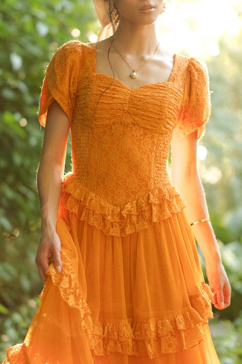 Step into a world of timeless tales and charm with the enchanting Raya dress. Its orange lace fabric and sweetheart neckline exude evermore, while the half length petal sleeves add a touch of whimsy. It features a maxi length skirt with a tiered tulle ruffle overlay. Vintage Orange Dress, Orange Dress Styling, Dark Formal Dresses, Yellow And Orange Wedding, Orange Ruffle Dress, Ruffle Dress Outfit, Orange Clothes, Orange Dress Wedding, Raya Dress