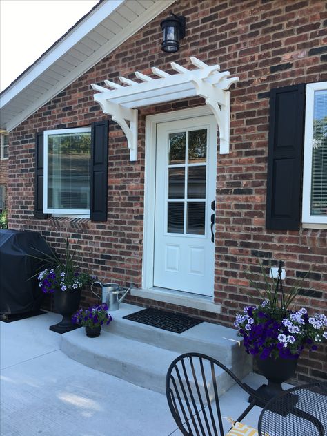 White over door pergola, red brick and black shutters. Pergola Over Doorway, Over The Door Pergola, Pergola Over Window Ideas, Front Door Pergola Entrance, Pergola Over Front Door, Front Door Arbor, Entry Pergola, Porch With Pergola, Front Door Pergola