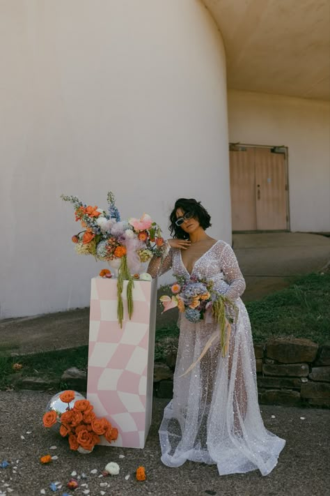 we love how hannah willis creative styled our white column for her styled shoot with daylilies! retro checkered vinyl, colorful florals, wedding decor inspo, modern bride, 2023 wedding trends, funky wedding decor, pinterest wedding ideas, dallas wedding photographer, dallas styled shoot, coral lane rentals, CL x EMERSON Funky Wedding Venues, Funky Garden Party Wedding, Modern Vibrant Wedding, Retro Wedding Theme Decor, Retro Garden Wedding, Kitch Wedding Ideas, Checker Wedding, Kitsch Wedding Decor, Funky Wedding Decor