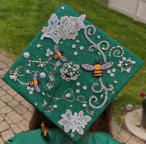 Aesthetic green emerald honey bee themed simple elegant graduation cap decoration with flowers and rhinestones, pearls and bee decals that is sparkly Graduation Cap Ideas Simple, Elegant Grad Cap Ideas, Graduation Cap Simple Design, Biology Major Graduation Cap, Bee Graduation Cap, Grad Cap Inspo High School, Rhinestone Graduation Cap Ideas, Lab Graduation Cap, Flower Graduation Cap Designs