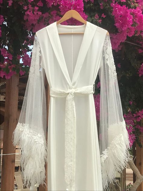 "Marlene" is a robe that will make you fall in love with it. It's waves of satin silk look attractive and are pleasant to the skin at once. Silk sash is covered by embroidered lace with beads, the same lace repeated at the ends of the sleeves, trimmed with genuine ostrich feathers. Complete look with a matching silk nightdress. #silknightgown #silkweddinglingerie #silkweddingdress #sheerlingerie #seethroughlingerie #bridalmorning #whitenightgown #whitelingerie #silkrobe #boudoirbride Robe With Feathers, Long Bridal Robe, Silk Bridal Robe, Silk Nightdress, Minimal Wedding Dress, Bride Lingerie, Honeymoon Lingerie, Look Attractive, Wedding Kimono