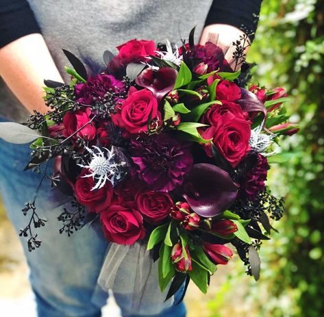 Deep red roses, black cally lilies, seeded eucalyptus painted black, thistle painted silvery white, red alstromeria, and deep, dark purple carnations combined to make this Halloween inspired bouquet. Purple Roses Wedding, Plum Wedding Flowers, Wedding Color Schemes Purple, Rose Centerpieces Wedding, Gothic Love, Purple Carnations, Thanksgiving Flowers, Dark Purple Flowers, Burgundy Bouquet