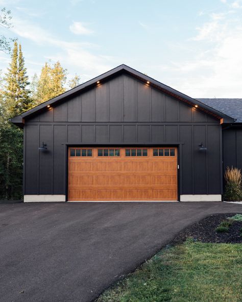 Benjamin Moore Black Siding Benjamin Moore Onyx with wood grain finish steel garage door #BenjaminMooreBlack #BlackSiding #BenjaminMooreOnyx #woodgraingaragedoor #steelgaragedoor #garagedoor Black And Galvanized Exterior, Black House With Black Garage Door, Cedar House Black Trim, All Black Exterior House With Wood, Black House Brown Garage Door, Black Steel Siding, Black Steel Siding Exterior House, Black Steel House Exterior, Homes With Black Siding