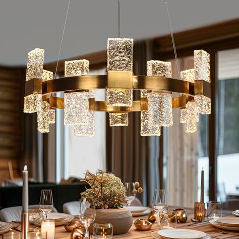 This 24-light LED chandelier with its drum silhouette, exudes contemporary elegance. It features an array of rectangular textured glass pieces that brilliantly diffuse light, creating a mesmerizing sparkle that illuminates any space. The design boasts a golden frame, providing a warm contrast to the cool glass, and is suspended from a sleek round canopy. Perfect for modern interiors, this fixture combines functionality with a striking aesthetic. LNC Euromos 31.1-in Large 24-Light Polished Gold Modern/Contemporary LED Dry rated Chandelier | HA05180 Dining Room Chandelier Round, Modern Chandeliers For Living Room, Boho Living Room Inspiration, Gold Light Fixture, Cool Glass, Short Glass, Led Crystal Chandelier, Wheel Chandelier, Glass Light Fixture