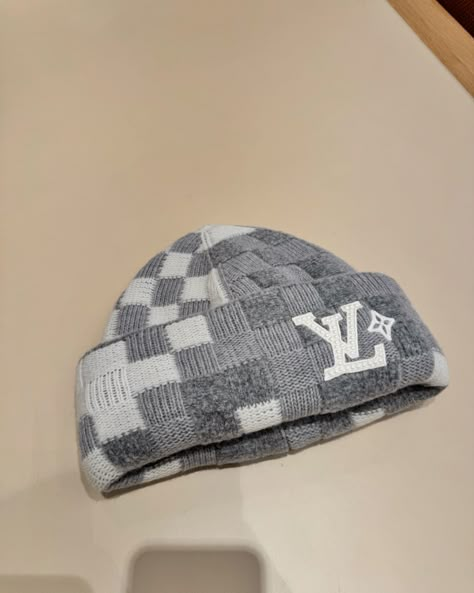 The soft, reversible LV Crush Beanie in light gray wool is covered in the Damoflage pattern, a pixelated blend of camouflage and the Damier print, that Pharrell Williams introduced at Spring-Summer 2024. On the bouclé side, the LV Lovers signature is embellished with pearls, and on the other, a jacquard LV signature is the focal point. #leaguefits #louisvuitton #louisvuittonbags #louisvuittonbag #louisvuittonaddict #louisvuittonlover #lvcommunity #lvworld #leaguefits #hypebeast #saks #fashi... Lv Beanie, Beanie Streetwear, Bape Jacket, Grillz Teeth, Guys Fashion Casual, Dope Hats, Wooly Hats, Drip Outfit Men, Classy Outfits Men