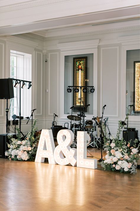 Two floral arrangements sit next to light up marquee letters (the couple's initials separated by an &). This decor was placed in front of the wedding band's equipment on the floor. Flowers were provided by Chicago florist, Romee Willow Florals. Dance Floor Decorations Wedding, Marquee Letters With Flowers, Wedding Dance Floor Decorations, Floor Flower Arrangements, Wedding Dance Floor, Marquee Letters Wedding, Light Up Marquee Letters, Wedding Cake Table Decorations, Simple Dance