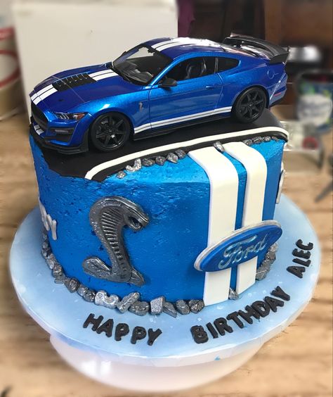 I made this cake for my son’s 11th birthday. This is his favorite car and wanted a cake to refect his live for this car. I made it into a 3 layer caje 10 inches in diameter. It is frosted with homemade buttercream and I put pie filling in between the cake layers. I frosted the cake in blue and then airbrushed a metalic blue food dye onto the fristing to give it a sheen. The decoations were all done in fondant. The car in top was purchase and is a 1:18 scale diecast mustang. Muscle Car Cakes For Men, Mustang Cars Birthday Cake, Race Car Birthday Cake For Men, Ford Mustang Cakes For Men, Car Cakes Design, Mustang Theme Birthday Party, Blue Car Birthday Cake, Mustang Car Cake, Mustang Cakes For Men