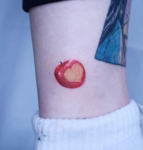 The apple, everyone's favorite fruit, is designed with red ink in this tattoo. Make a heart on one side of the apple tattoo to express your affection for the apple fruit. This tattoo is appropriate for males and females and... Mini Apple Tattoo, Apple Heart Tattoo, Cute Apple Tattoo, Apple Of My Eye Tattoo, Bitten Apple Tattoo, Apple Pie Tattoo, Fruit Bowl Tattoo, Apple Core Tattoo, Apple Tattoo Design