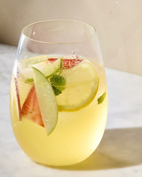 angled shot of a glass of white sangria, with lime, mint and strawberry in the glass Easy White Sangria, Christmas Margaritas, Strawberry Basil Margarita, Sangria Punch, White Sangria Recipe, Pitcher Cocktails, White Wine Sangria, Being Social, Wine Sangria