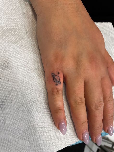 Tiny finger tat saturn tattoo space stars Star Finger Tat, Universe Finger Tattoo, Saturn Tiny Tattoo, Mini Saturn Tattoo, Saturn Hand Tattoo, Mini Space Tattoo, Saturn Tattoo With Stars, Dainty Saturn Tattoo, Saturn Heart Tattoo