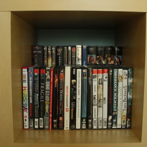 Double DVD storage space by placing a raised shelf (this one is a wood shelf sitting on top of upside down large candle holders - but could use anything) in the back of a bookcase ... clever! Dvd Storage Ideas Diy, Ikea Dvd Storage, Dvd Storage Tower, Dvd Storage Ideas, Dvd Storage Cabinet, Diy Dvd Storage, Diy Dvd, Dvd Storage Shelves, Dvd Organization