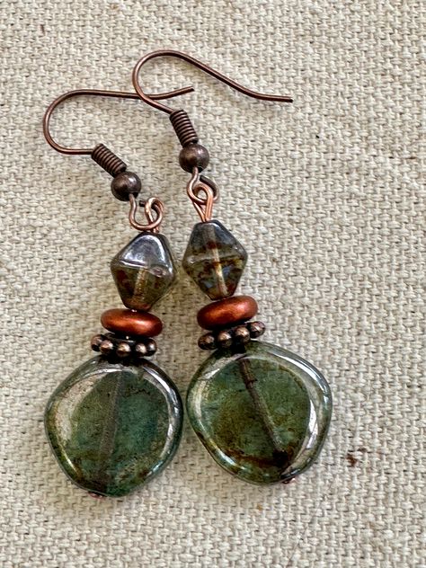 Beautiful  transparent Lumi green glass.  An earthy picasso coat is added giving earthy touches to the entire surface of the coin beads. They are beautiful coin beads. They have a matching 8mm beautiful and earthy pine green bicone glass bead.  They have a glossy fire polished lumi finish. The earrings dangle an inch on Copper Ear Wires.  The copper accents bring out the earthy feeling of these unique earrings. Perfect for work or casual anytime of year. UniquelybyRuth pays for your first class shipping when your order is $35 or more, so take a look around the shop and see if anything else calls to you! 🆓 Chip Bead Earrings, Earth Decor, Earthy Jewelry, Glass Bead Earrings, Belly Jewelry, Stylish Earrings, Copper Accents, Funky Jewelry, Pine Green